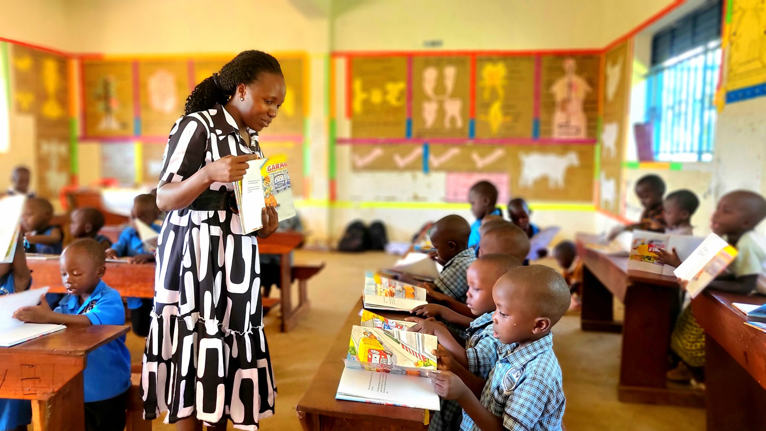 Teacher stands at the front of a fully engaged class, books open across every desk