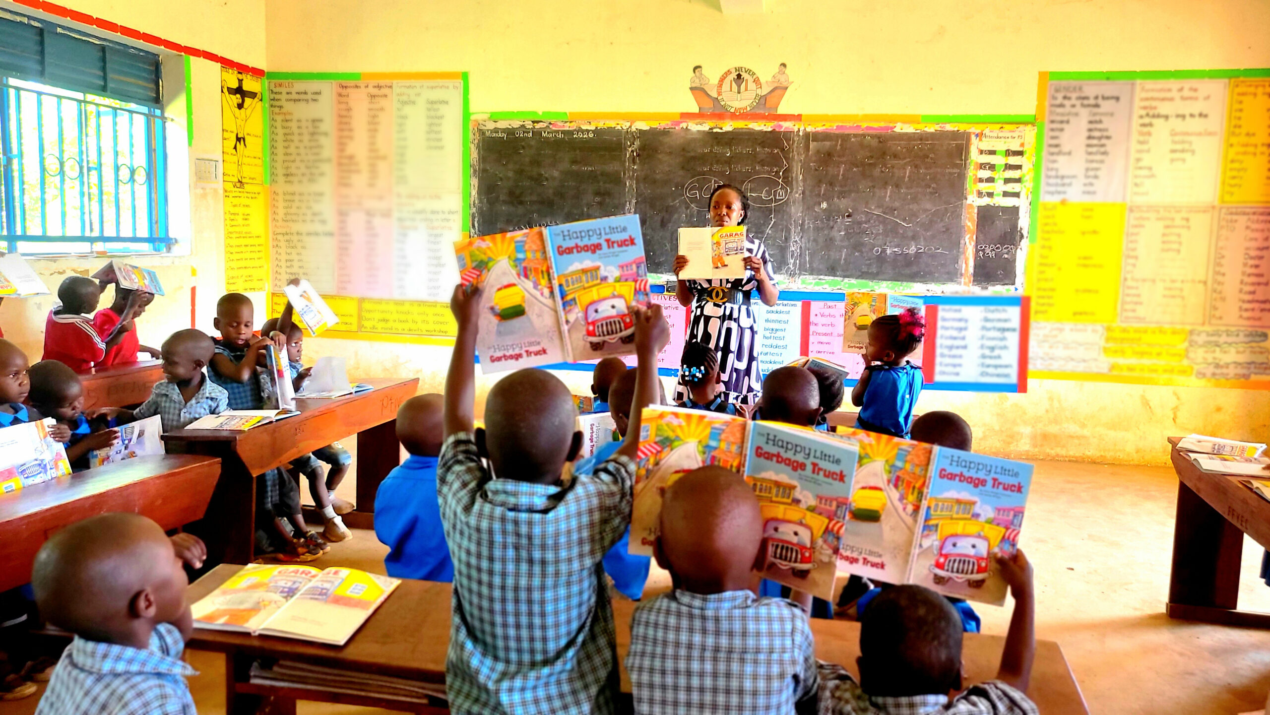 A full classroom of FFYEC learners proudly hold up their individual storybooks