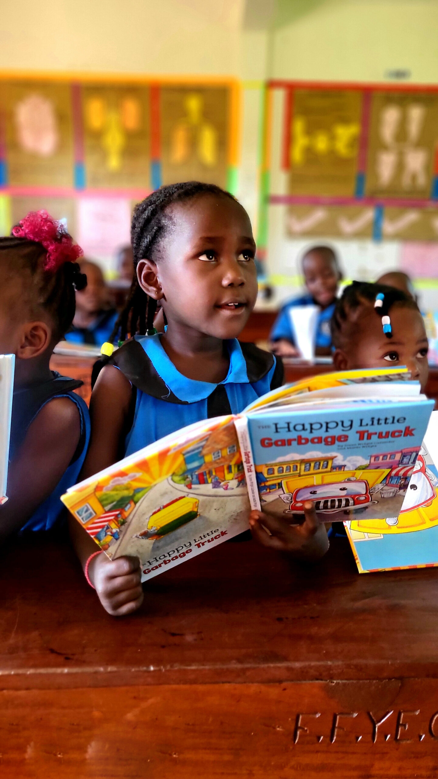 Close portrait of a young girl holding her storybook with wide, curious eyes — pure wonder