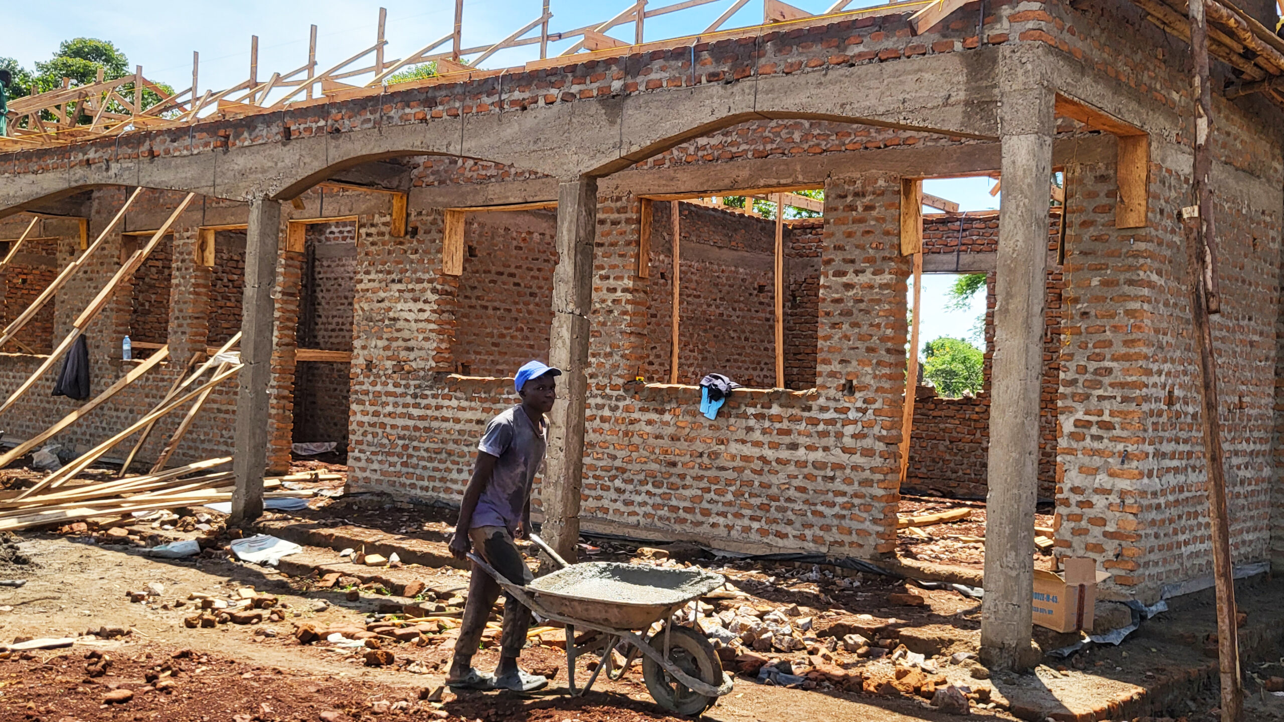 Worker pushing a wheelbarrow of cement at the FFYEC construction site